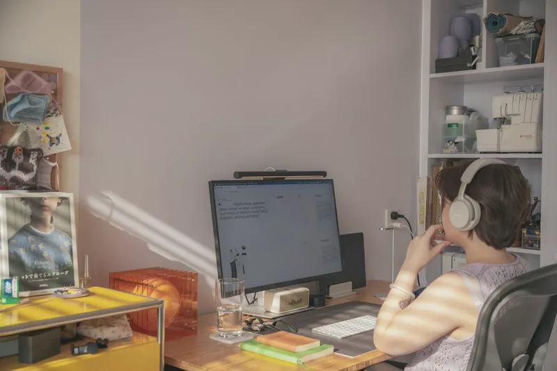 A person with headphones working at a desk in a quiet home office.